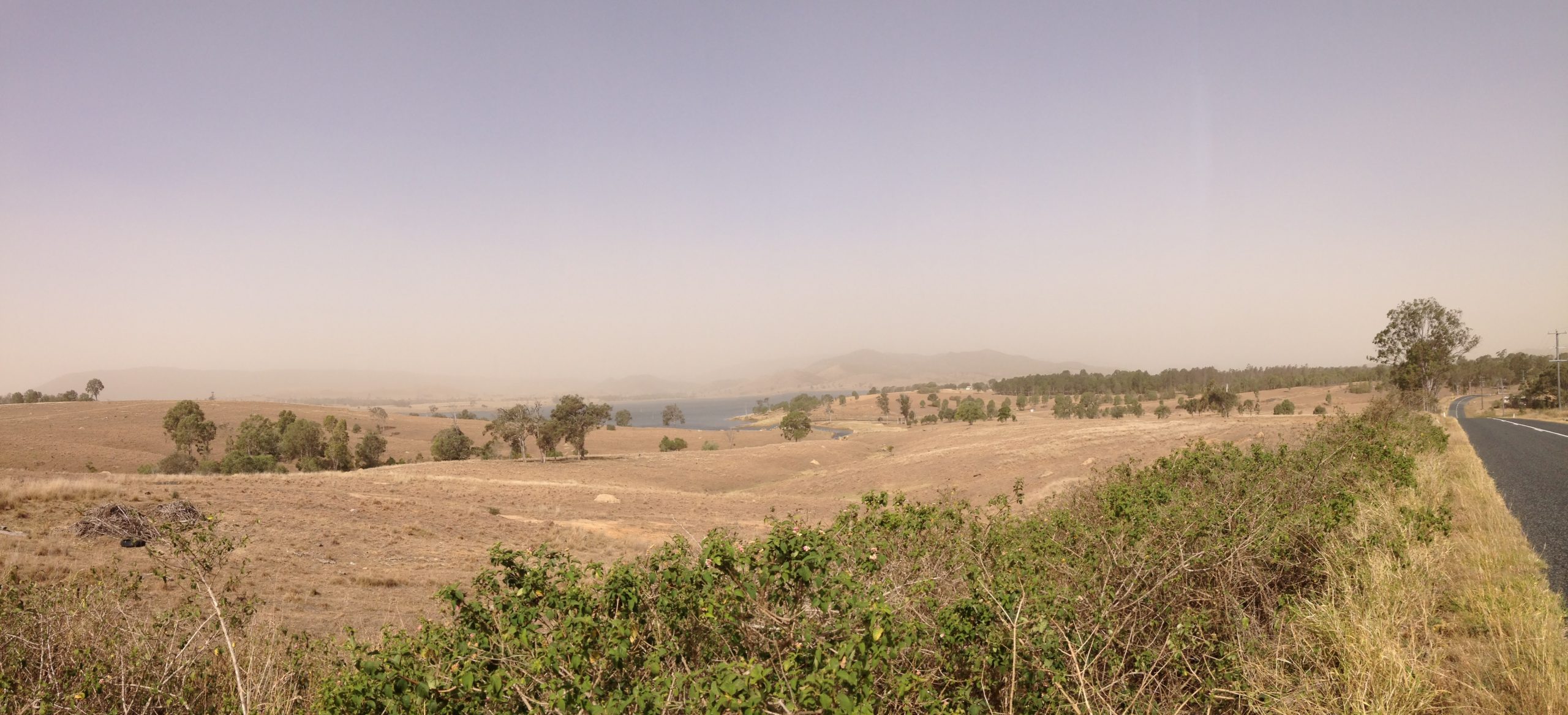 Vista from the side of the road. Brown landscape, nothing in the distance but brown dusty sky.
